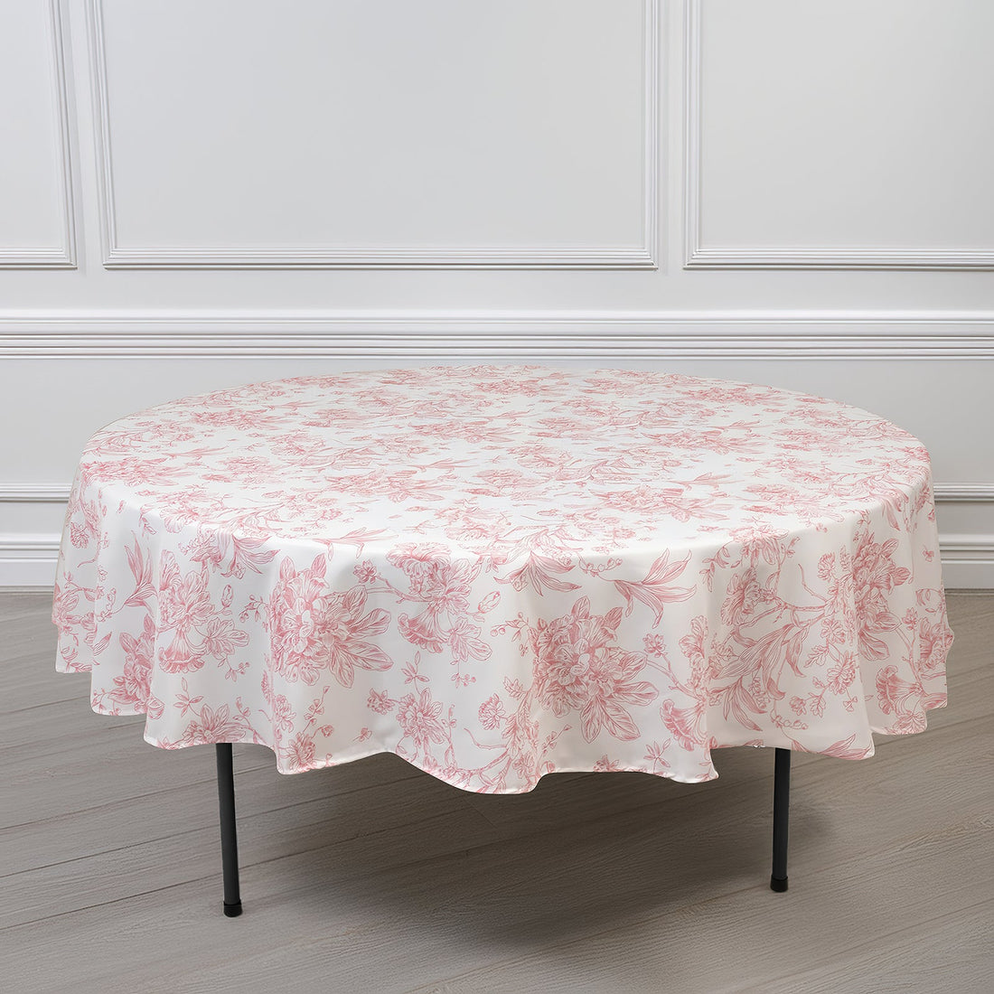 Round floral tablecloth in pink and white on a plain background.