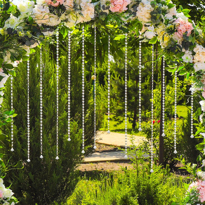 Beautiful floral arch with hanging crystals in a lush garden setting.