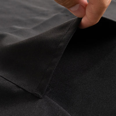 Close-up of a hand pulling back black fabric showing texture and detail.
