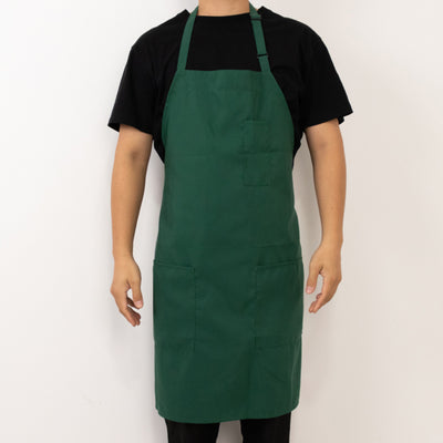 Green apron worn by a person, featuring pockets and adjustable ties.