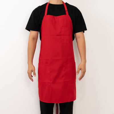 Red apron worn by a person with pockets for cooking or crafting.