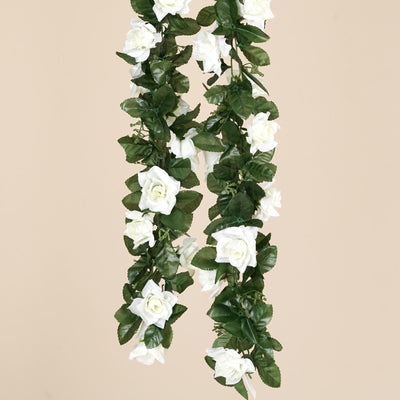 White rose garland with green leaves on a beige background.