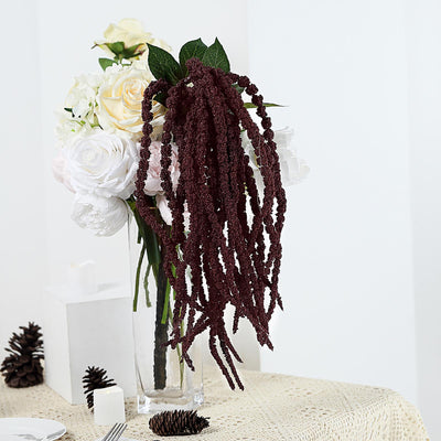 Decorative burgundy floral arrangement in a clear vase with white flowers.