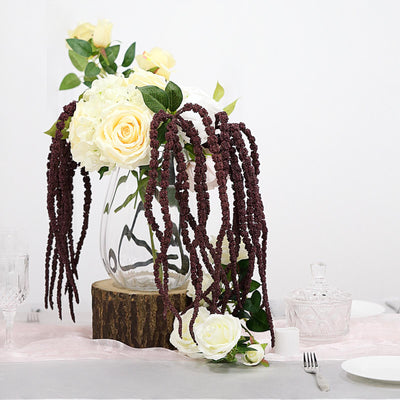 Floral arrangement with roses and cascading foliage in a glass vase.