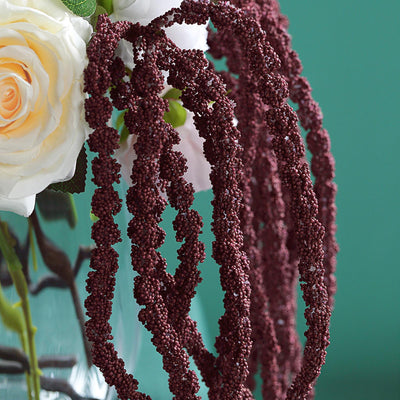 Decorative burgundy amaranth strands intertwined with flowers in a vase.