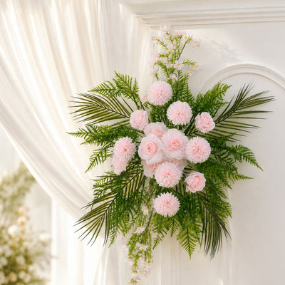 Soft pink floral arrangement with green foliage on a white wall, elegant decor