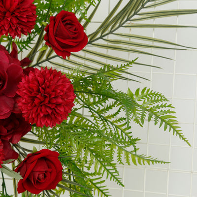 Red roses and vibrant flowers with green foliage on a white background.