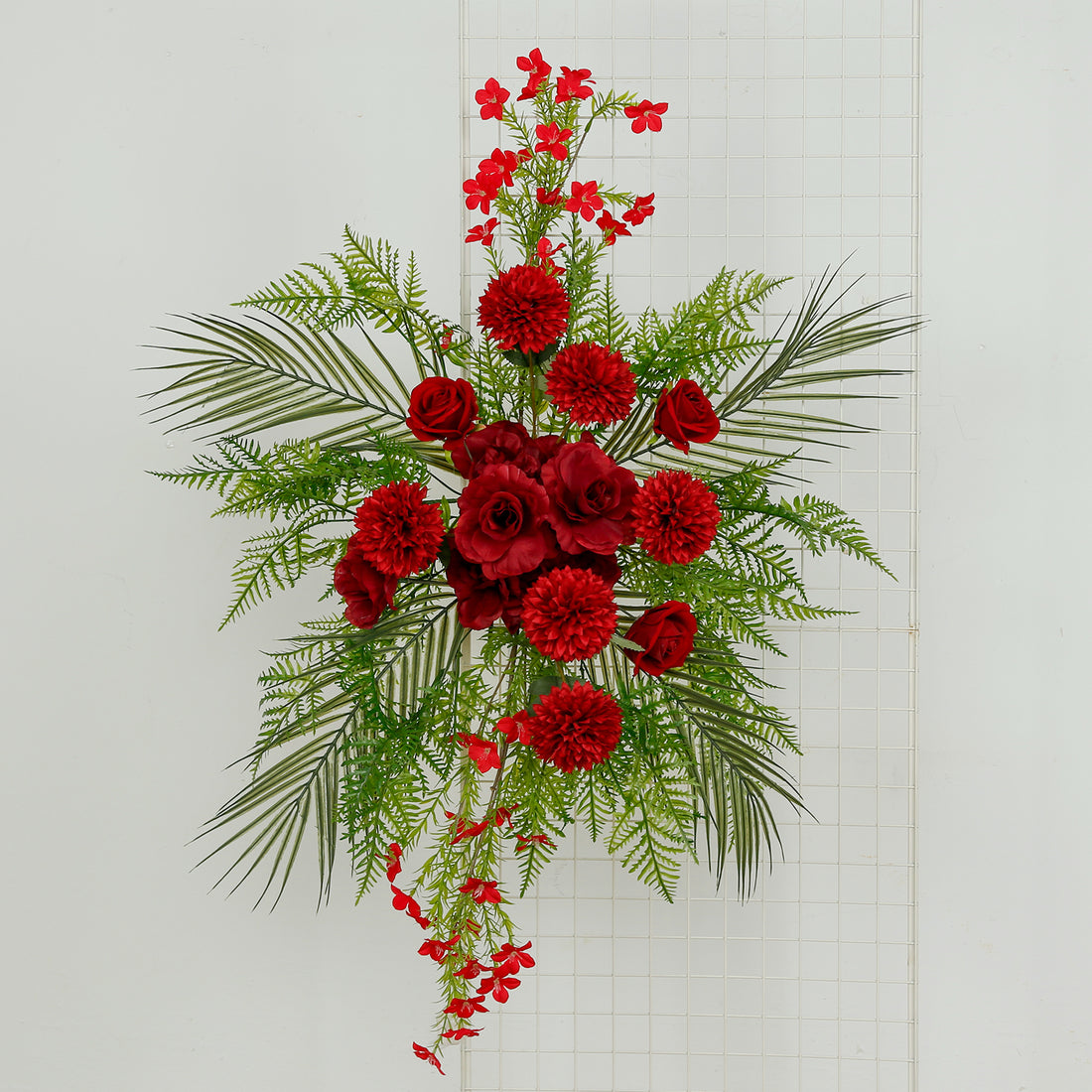 Artificial red floral arrangement with greenery on a white background