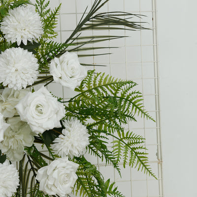 White floral arrangement with roses and greenery against a white backdrop.