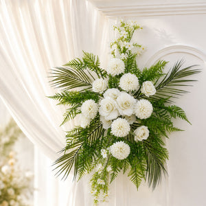 White floral funeral arrangement with roses and greenery on a white backdrop