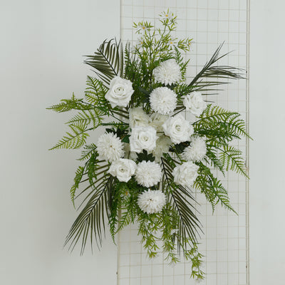 White floral arrangement with roses and greenery on a grid backdrop.