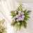 Pastel pink floral arrangement with roses and greenery on a white wall