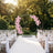 Outdoor wedding ceremony aisle with pink floral circle arch and white chairs