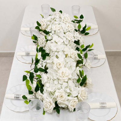 Elegant white floral table runner with green leaves and clear glassware