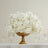 White floral arrangement in a gold vase with crystal glasses.