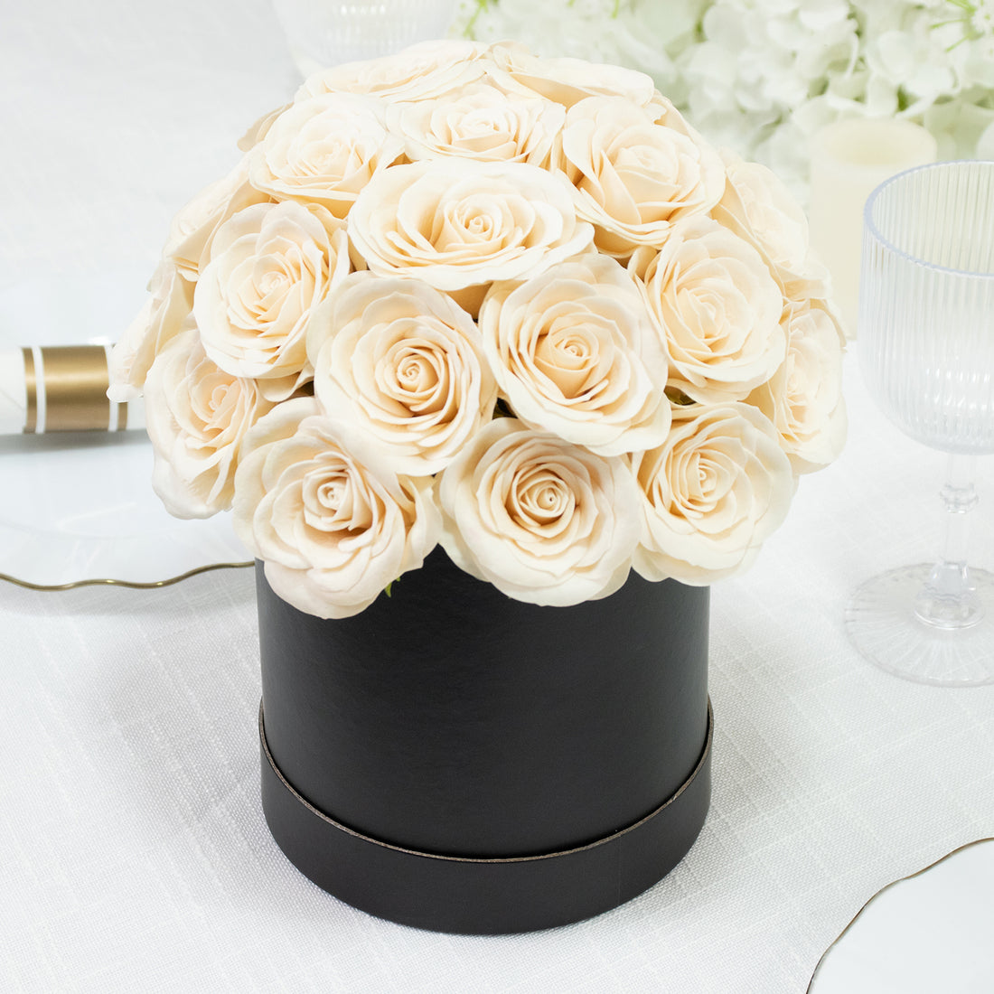 Cream rose bouquet in a black round box on a table setting.