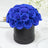 Blue rose bouquet in a black round box on a white table setting.