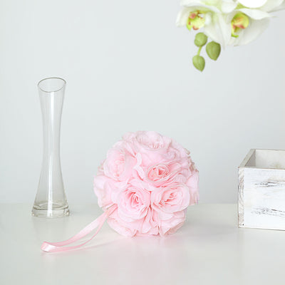 Pink fabric rose bouquet on a white table with a glass vase and wooden box.