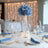 Blue rose bouquet centerpiece with fairy lights on elegantly set dining table.