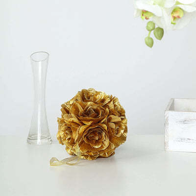 Gold decorative flower arrangement with ribbon on a white surface.