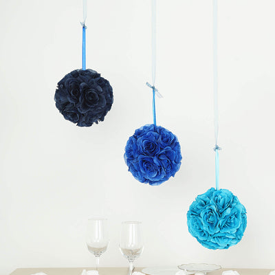 Hanging fabric flower balls in blue shades above a table setting with glasses.