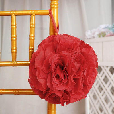 Red floral pomander hanging from a chair in a decorated setting.