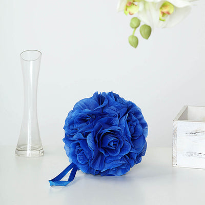 Blue floral bouquet on a white surface with a glass vase and wooden box.