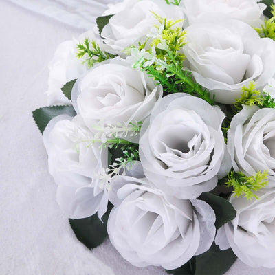 White artificial rose bouquet with green accents on a soft surface.