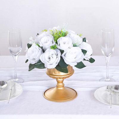 White rose floral arrangement in a gold vase on a table.
