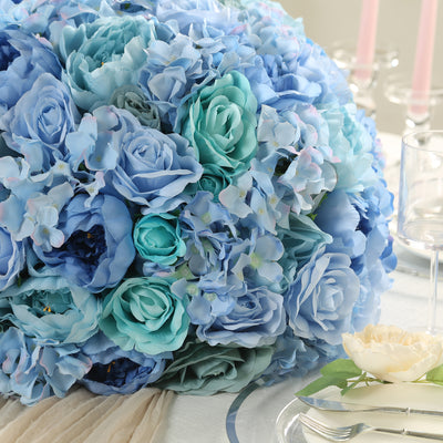 Blue floral arrangement with roses and hydrangeas on a table setting.