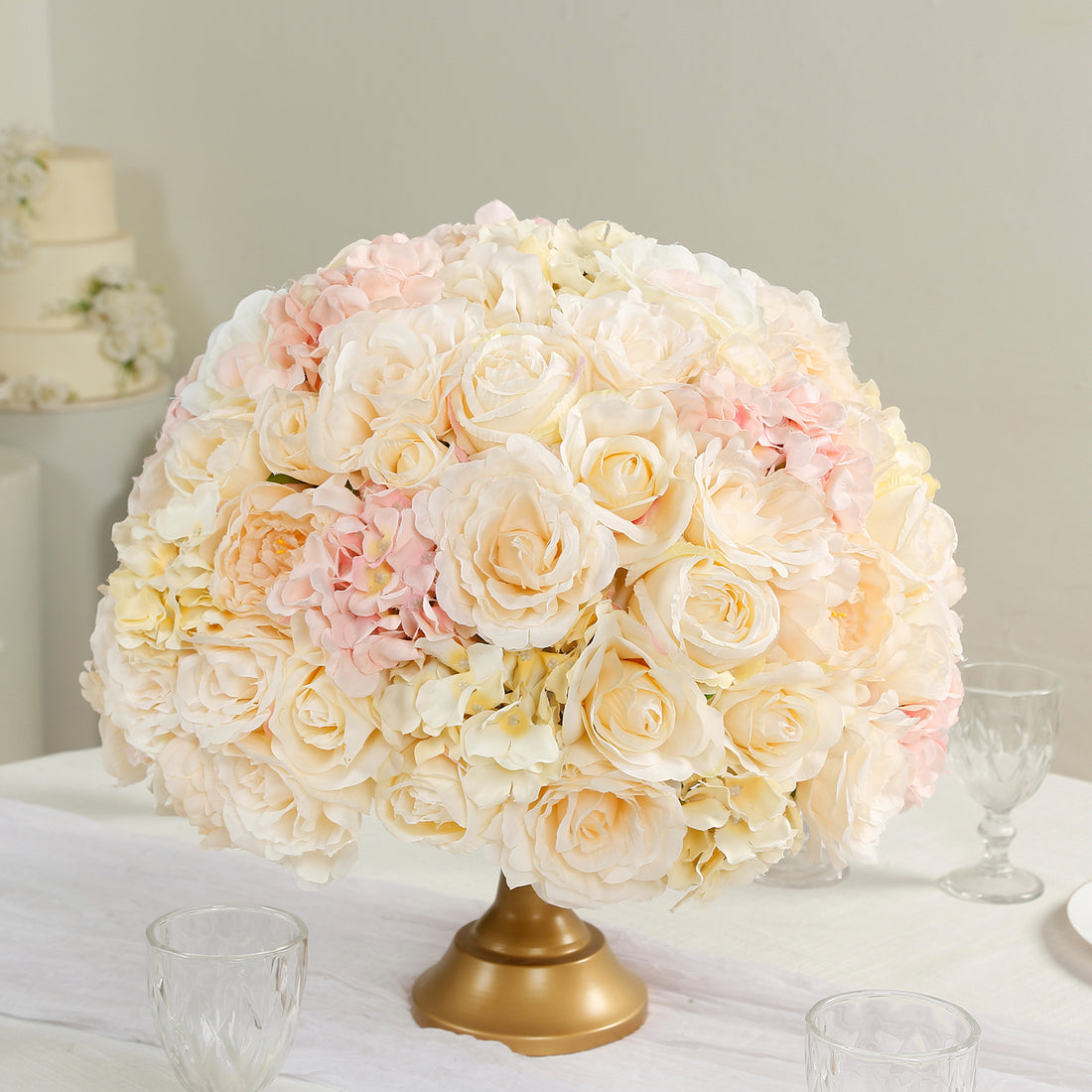 Elegant floral centerpiece with soft pink and cream roses in a gold vase.