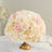 Elegant floral centerpiece with soft pink and cream roses in a gold vase.