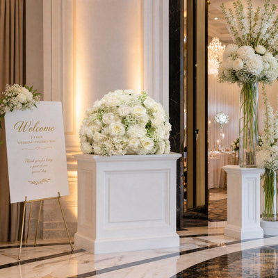Elegant wedding reception entrance with white floral arrangements and welcome sign
