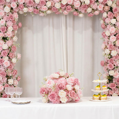 Pink rose floral dessert table backdrop with cupcakes and glassware