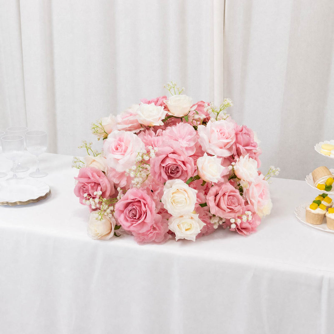 Pink and white rose bouquet centerpiece with cupcakes on a white table