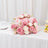 Pink and white rose bouquet centerpiece with cupcakes on a white table
