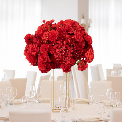 Red floral centerpiece in an elegant dining setting.