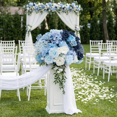 Blue and white wedding ceremony floral arch with chairs and petal aisle