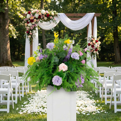 Outdoor wedding ceremony arch with floral arrangements and white drapery