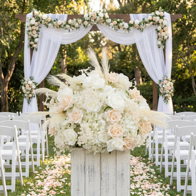 Elegant outdoor wedding ceremony with white floral arch and aisle flowers