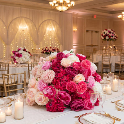 Elegant pink and white floral wedding reception table centerpiece with candles