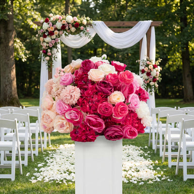 Outdoor wedding arch with pink and white floral arrangements and white chairs