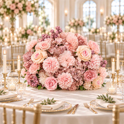 Pink floral wedding centerpiece with candles on an elegant gold table setting