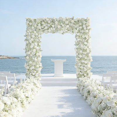 Elegant floral wedding arch by the sea with white flowers and a ceremony podium.