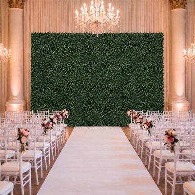 Elegant wedding ceremony setup with white chairs, floral accents, and green backdrop