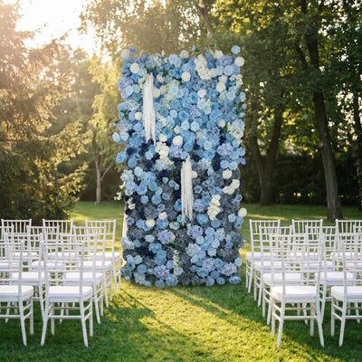 Outdoor wedding ceremony setup with blue floral backdrop and white chairs