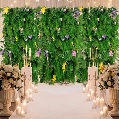 Luxury wedding aisle with lush green floral wall, candles, and white blooms