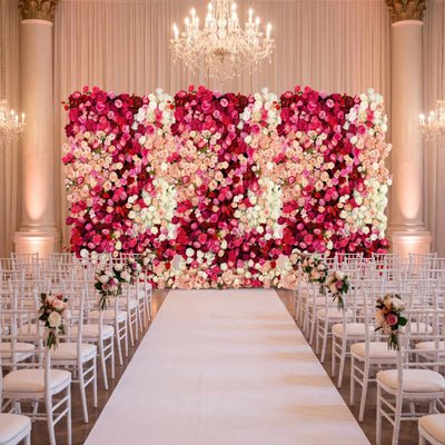 Luxury wedding ceremony aisle with pink floral wall, white chairs, and chandeliers