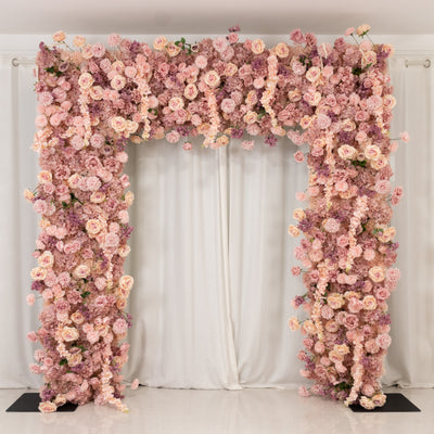 Floral archway adorned with pink and purple roses against a white backdrop.