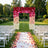 Outdoor wedding ceremony aisle with floral arch and white chairs in garden